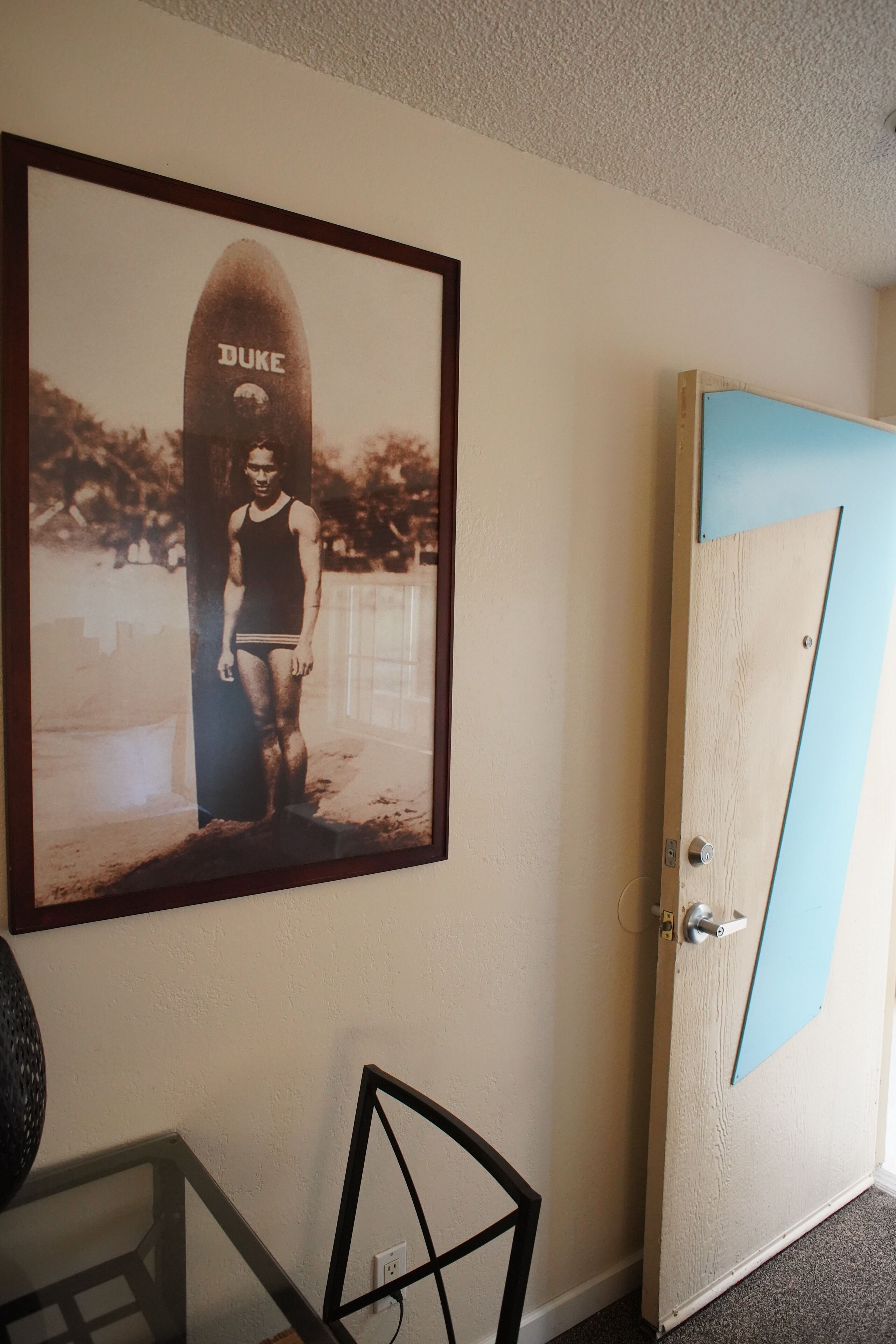 Ein gerahmtes Foto einer Person mit einem Surfbrett mit der Aufschrift 'DUKE' an einer Wand.