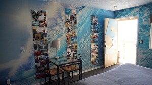 Une pièce comprenant un lit, un bureau avec une chaise et un mur décoré de diverses photos.