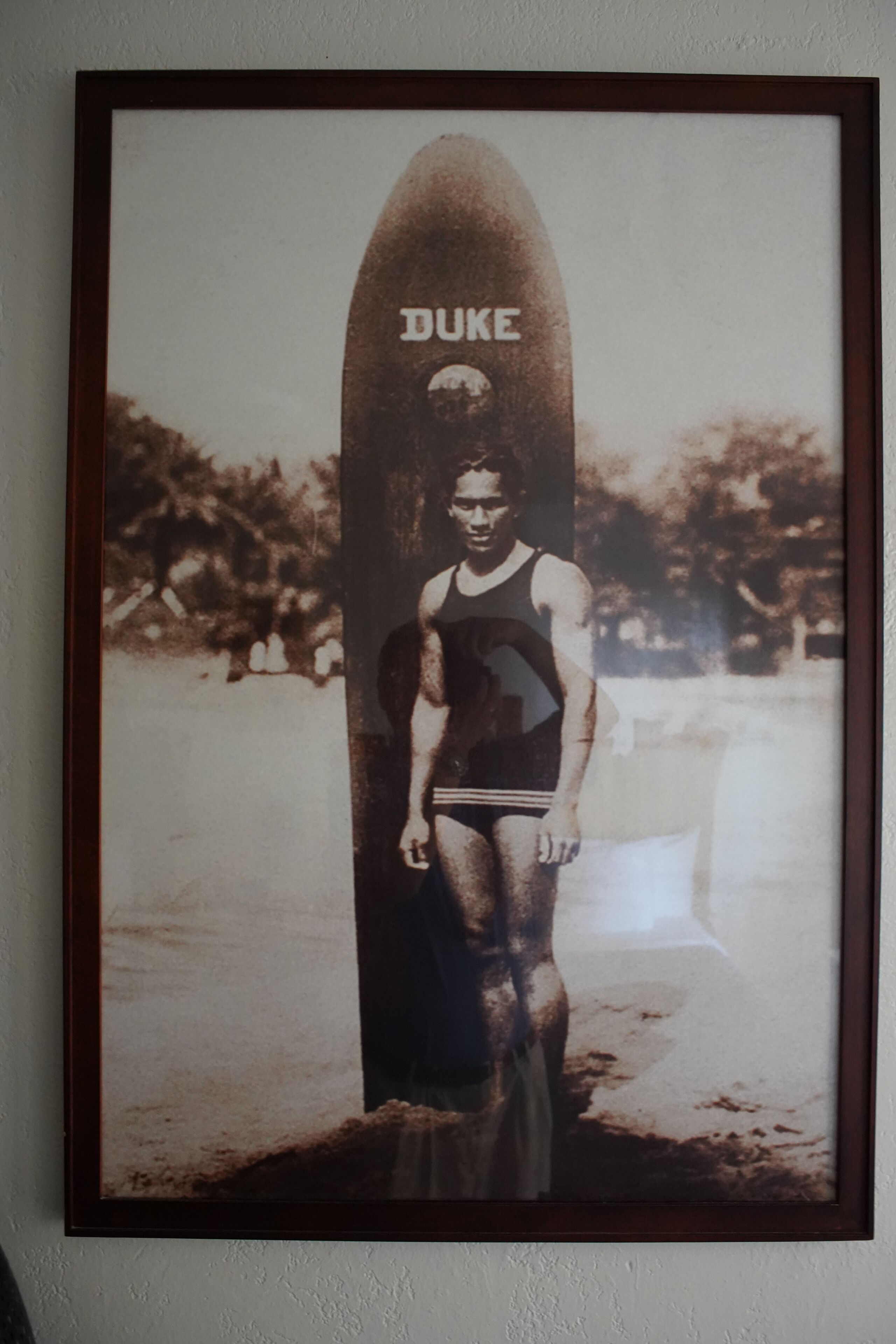 A framed photograph of a person standing on a surfboard with the word "DUKE" on it.