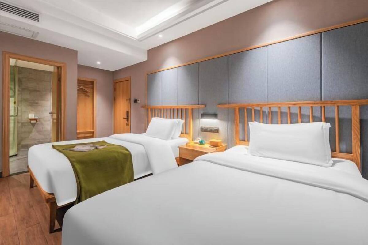 A hotel room with two beds, a wooden headboard, a nightstand, and a mirror.