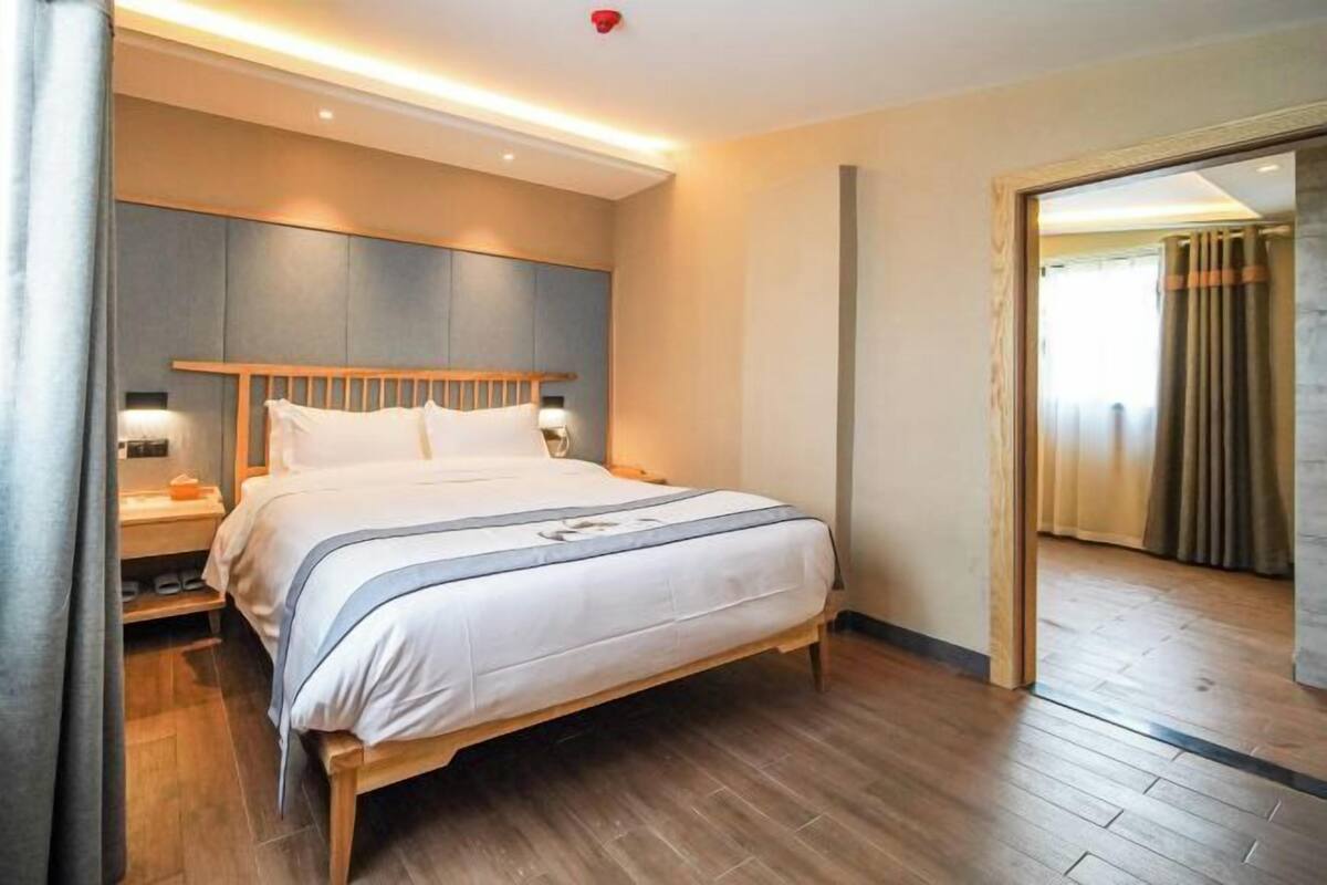 A modern hotel room with a wooden bed, bedside tables, and a large mirror.