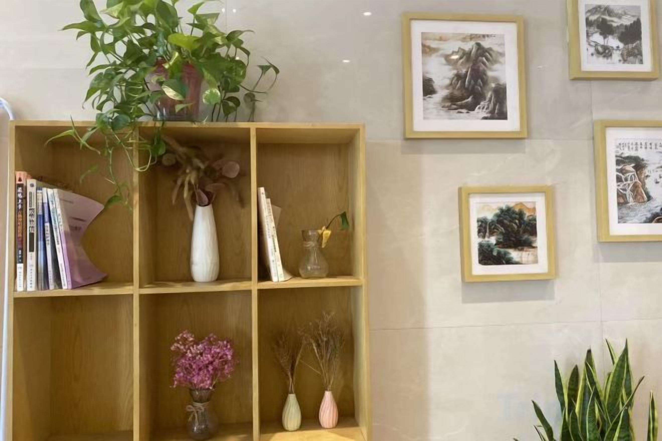 A wooden bookshelf with various items including books, a vase with flowers, and a plant.
