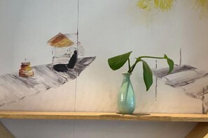A painting with a vase and a book on a shelf.