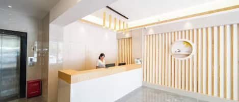 A modern reception area with a receptionist, a reception desk, and a wall with vertical wooden slats.