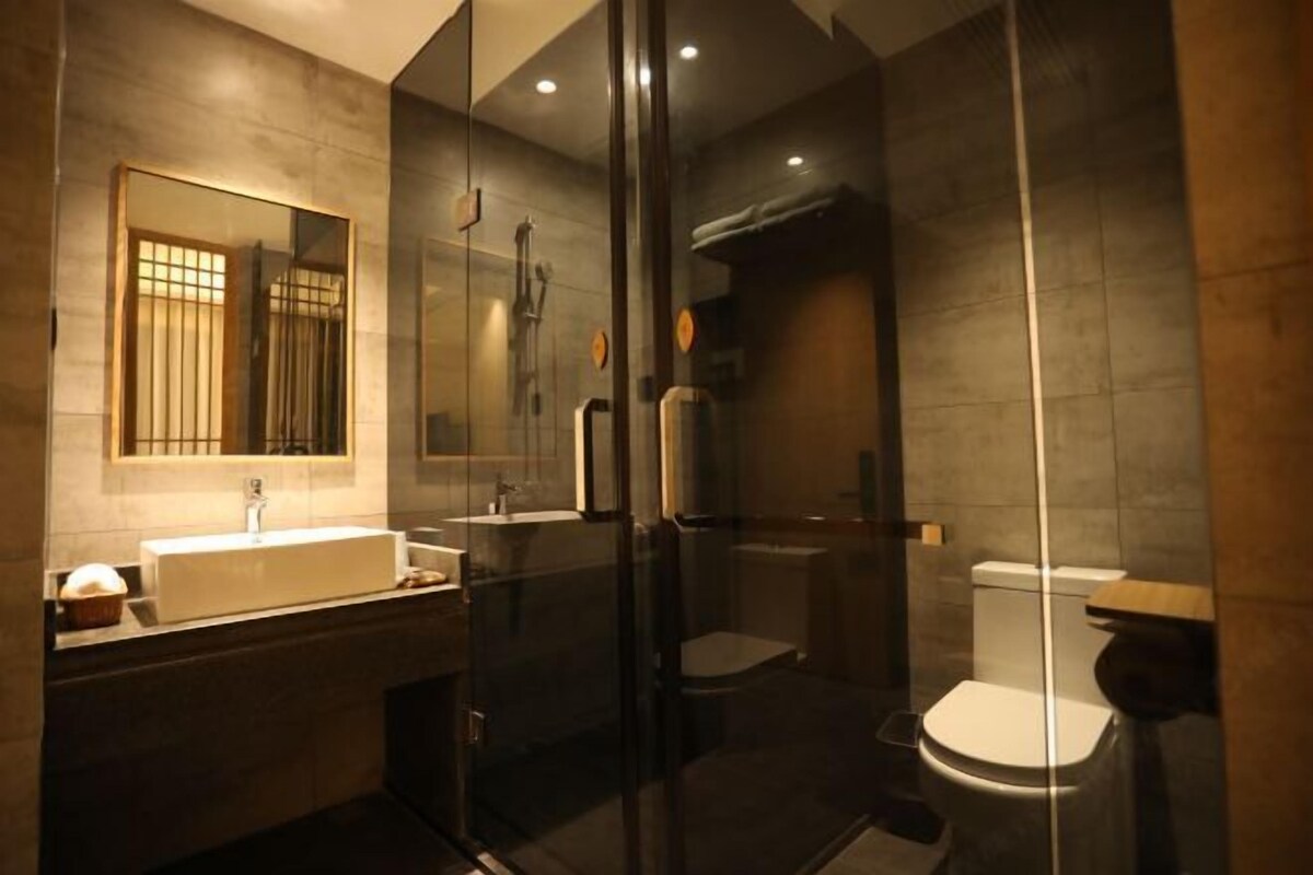 A modern bathroom with a glass-enclosed shower, a large mirror, and a white sink.