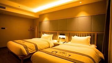 A hotel room with two beds, a wooden headboard, and a nightstand with a lamp.