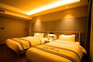 Una habitación de hotel con dos camas, un cabecero de madera y una mesita de noche con una lámpara.