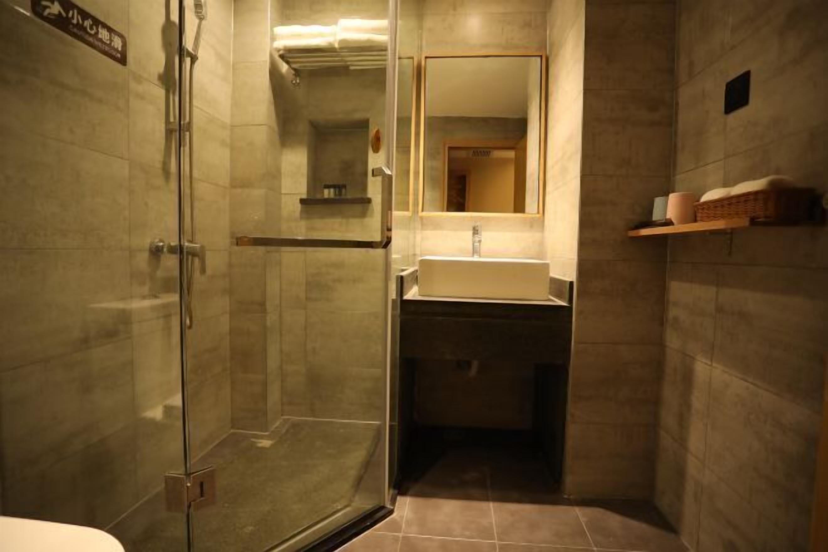 A small, modern bathroom with a glass shower enclosure, a sink, and a mirror.