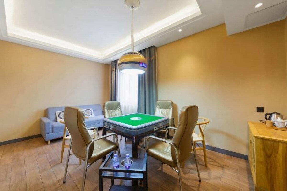 A room with a pool table, four chairs, a sofa, and a small table with a kettle.