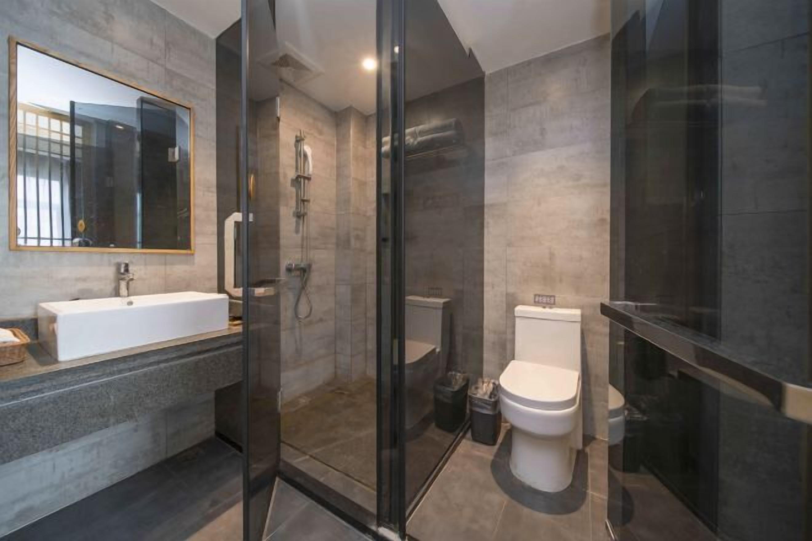 A modern bathroom with a glass-enclosed shower, a white sink, and a toilet.