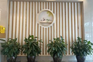 A reception area with a wooden slat wall, a circular mirror, and potted plants. - zhuzijianHotel (Yueyang)