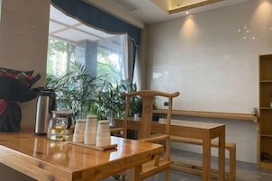 A wooden table with a chair, a coffee machine, and a glass jar on a counter.