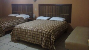 Una habitación con dos camas, cada una con cabecera y almohadas.