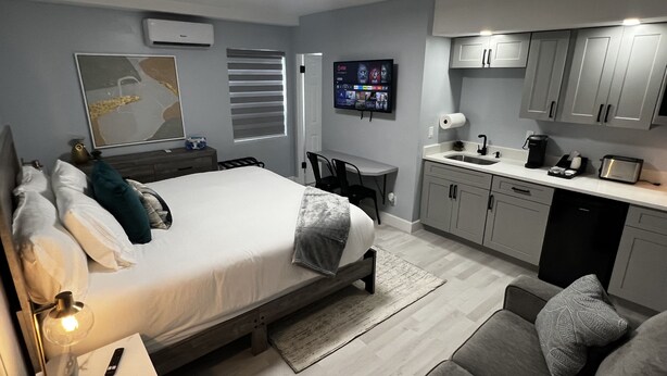 Ett modernt sovrum med en säng, ett sängbord och en tv som är monterad på väggen.