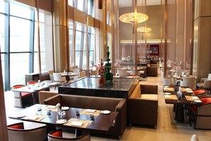A spacious restaurant with high ceilings and large windows, featuring multiple dining tables and booths. - Primus Hotel (Shenyang)