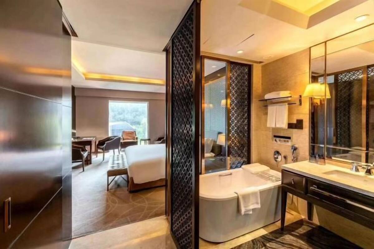 A modern hotel bathroom with a large bathtub, a separate shower area, and a vanity with a mirror.