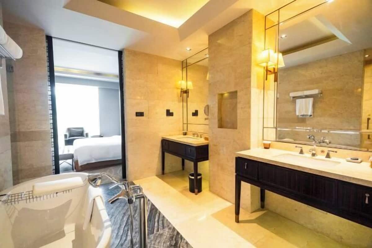 A modern bathroom with a bathtub, two sinks, and a large mirror.