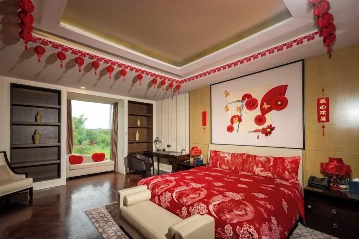 A bedroom with a bed, a desk, and a window.