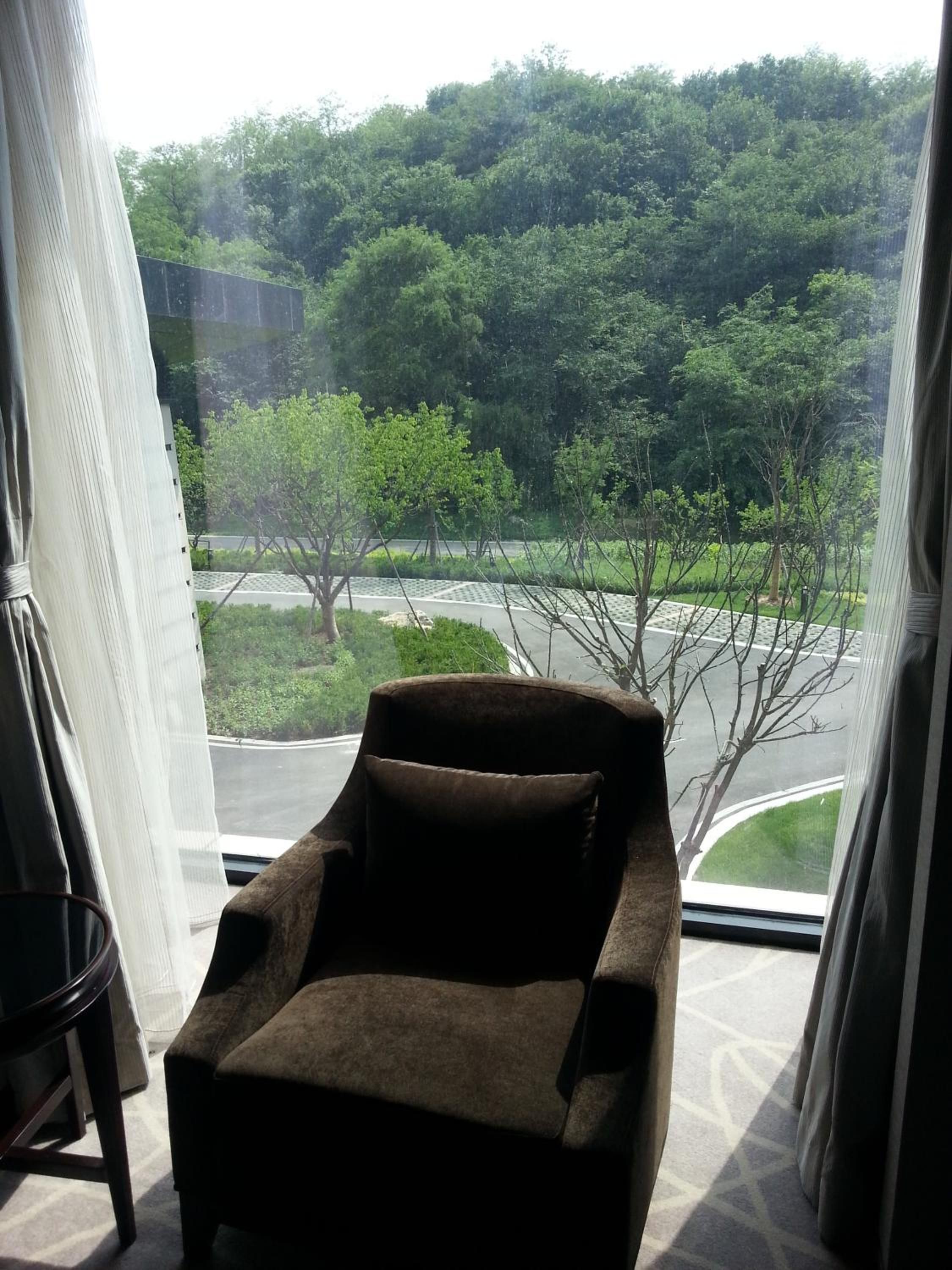 A room with a large window offering a view of a road and greenery outside.