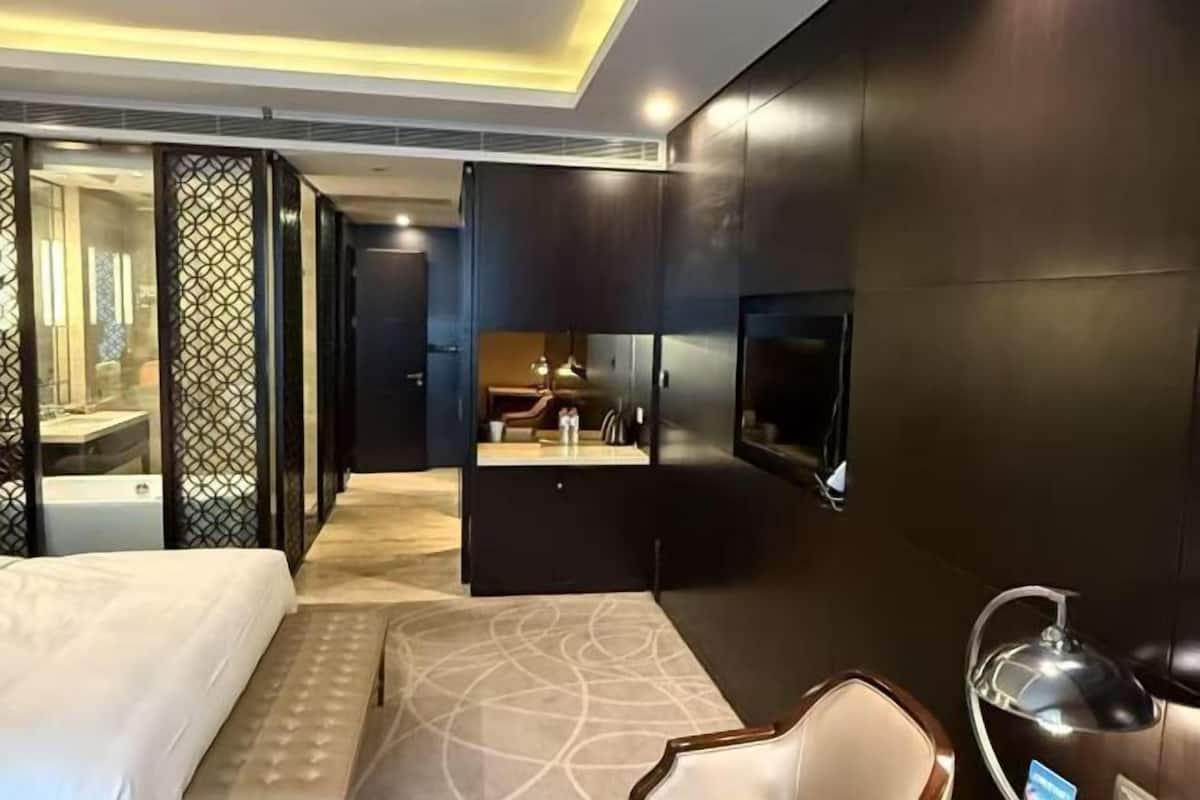 A hotel room with a bed, a desk, a TV, and a bathroom.