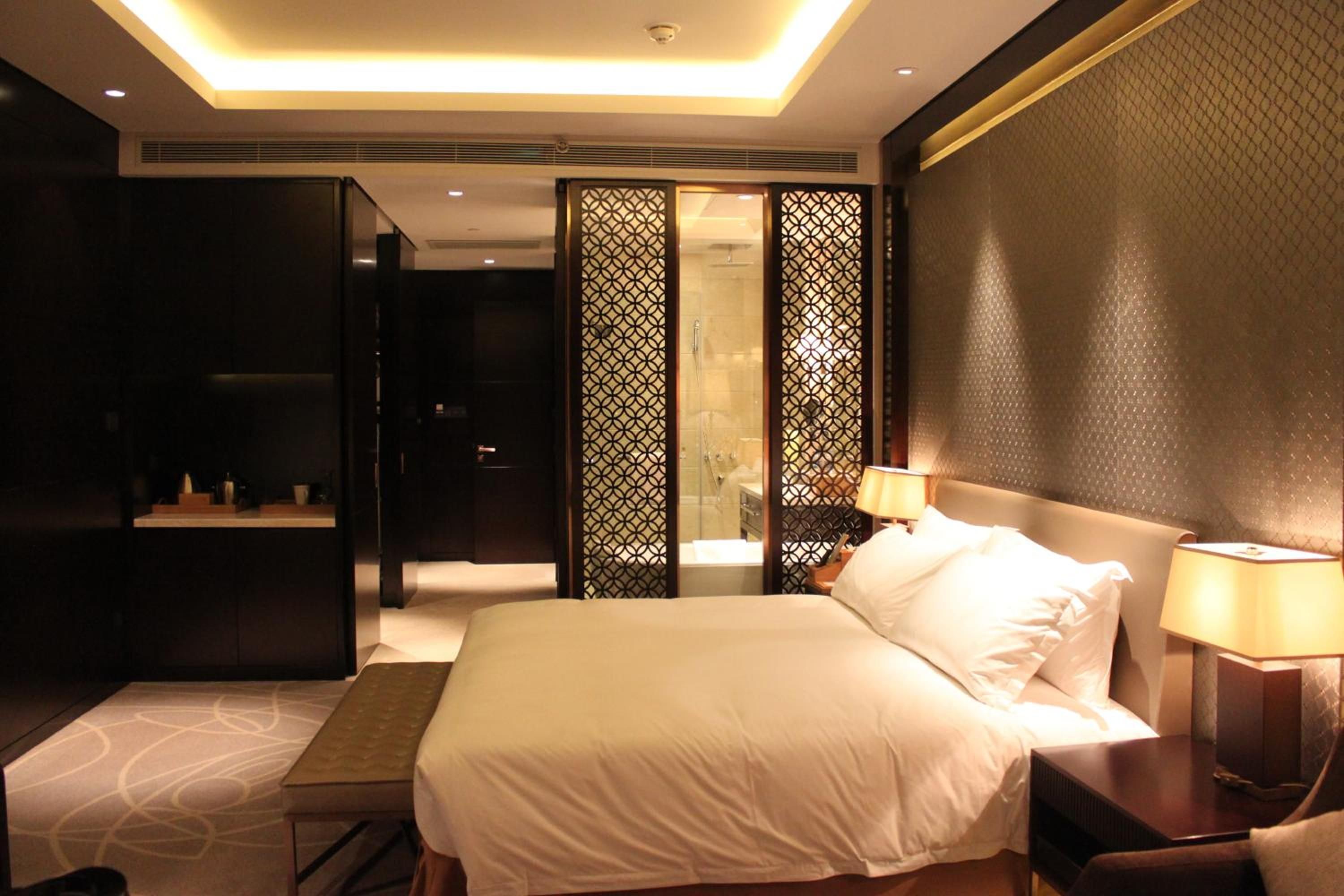 Een hotelkamer met een groot bed, nachtkastjes, een bureau en een douche.