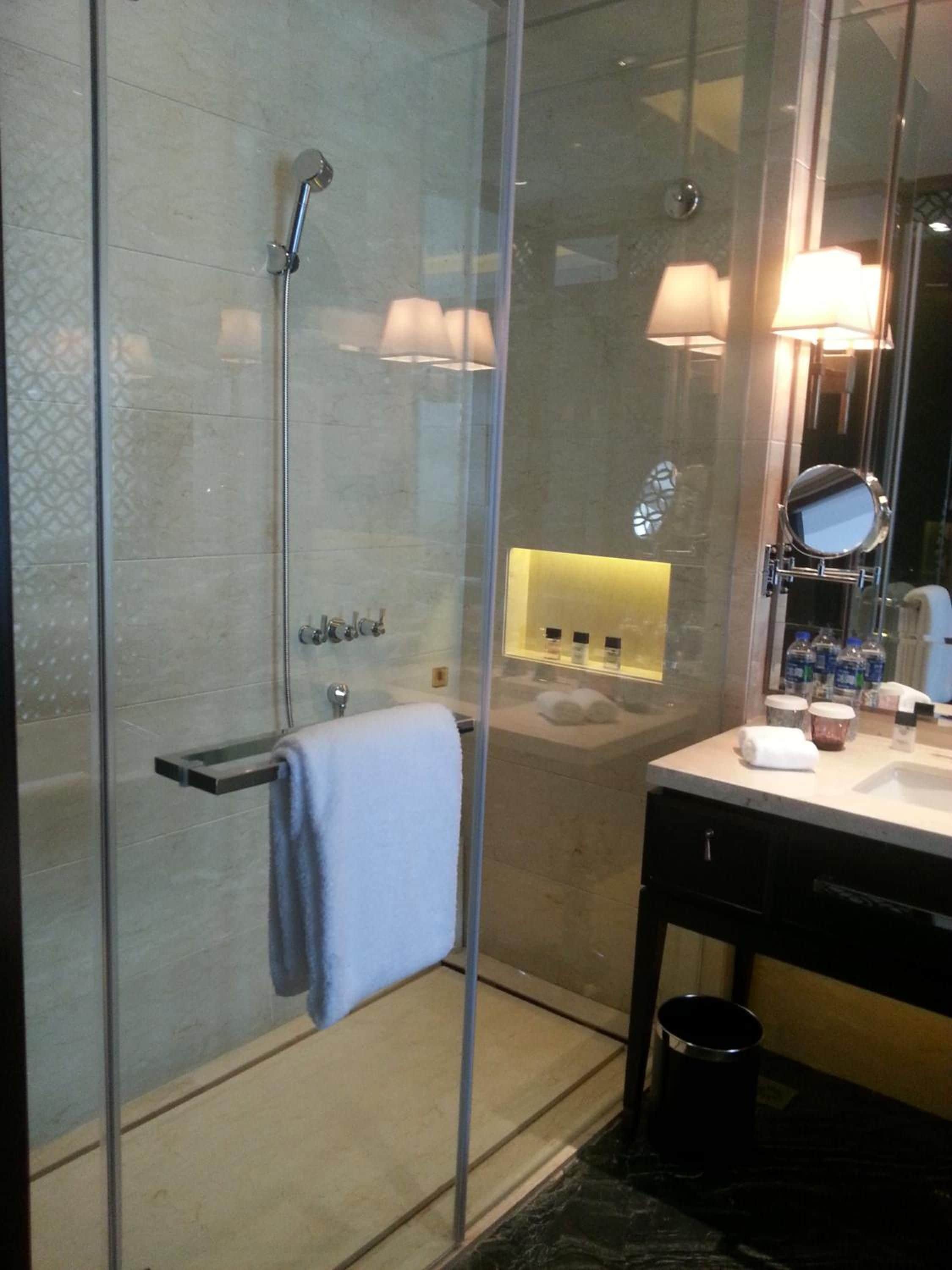 Een moderne badkamer met een douchecabine van glas, een wastafel met spiegel en een wasbak.