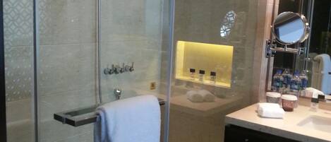Een moderne badkamer met een douchecabine van glas, een wastafel met spiegel en een wasbak.