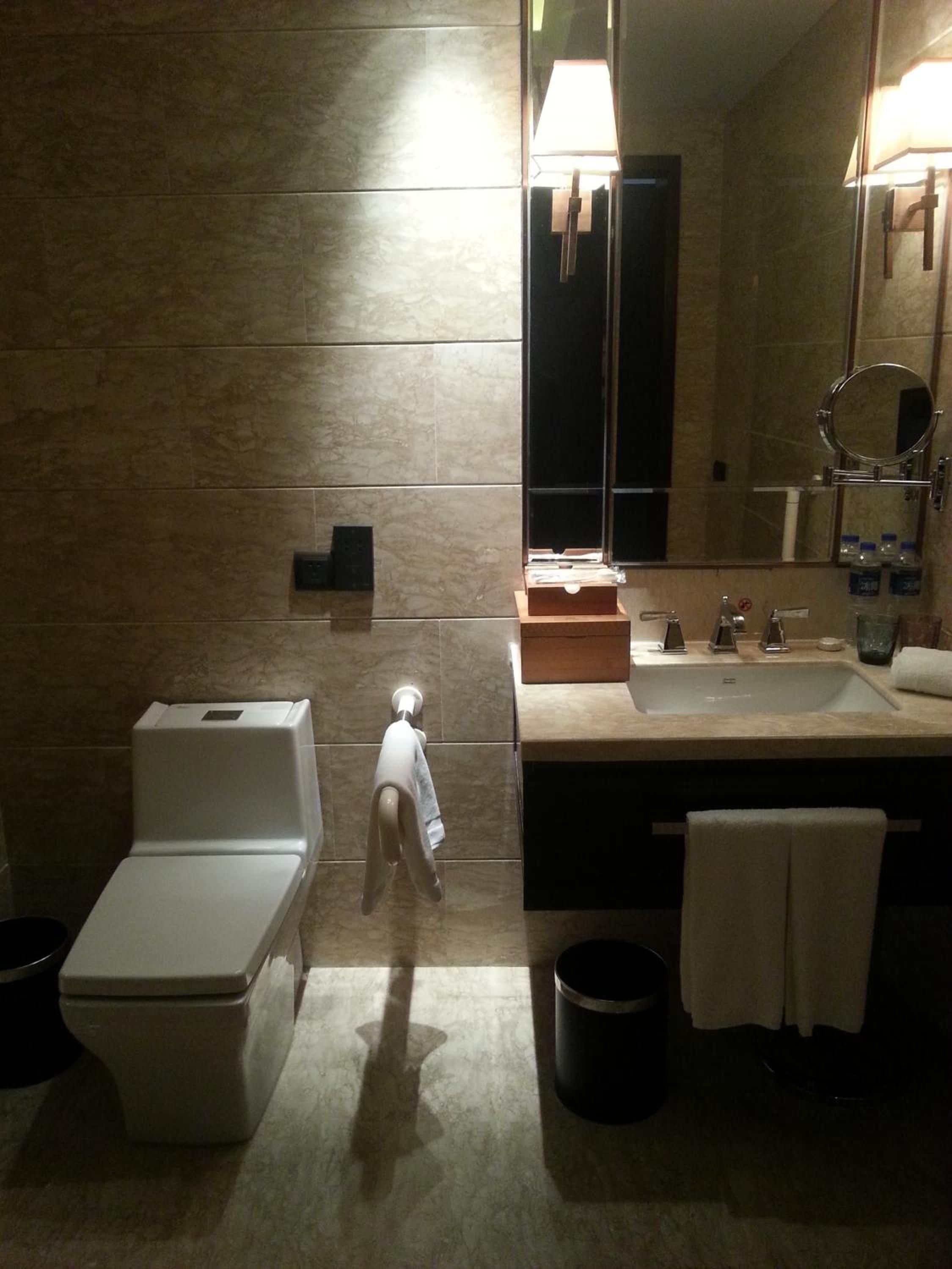 A bathroom with a toilet, sink, and mirror.