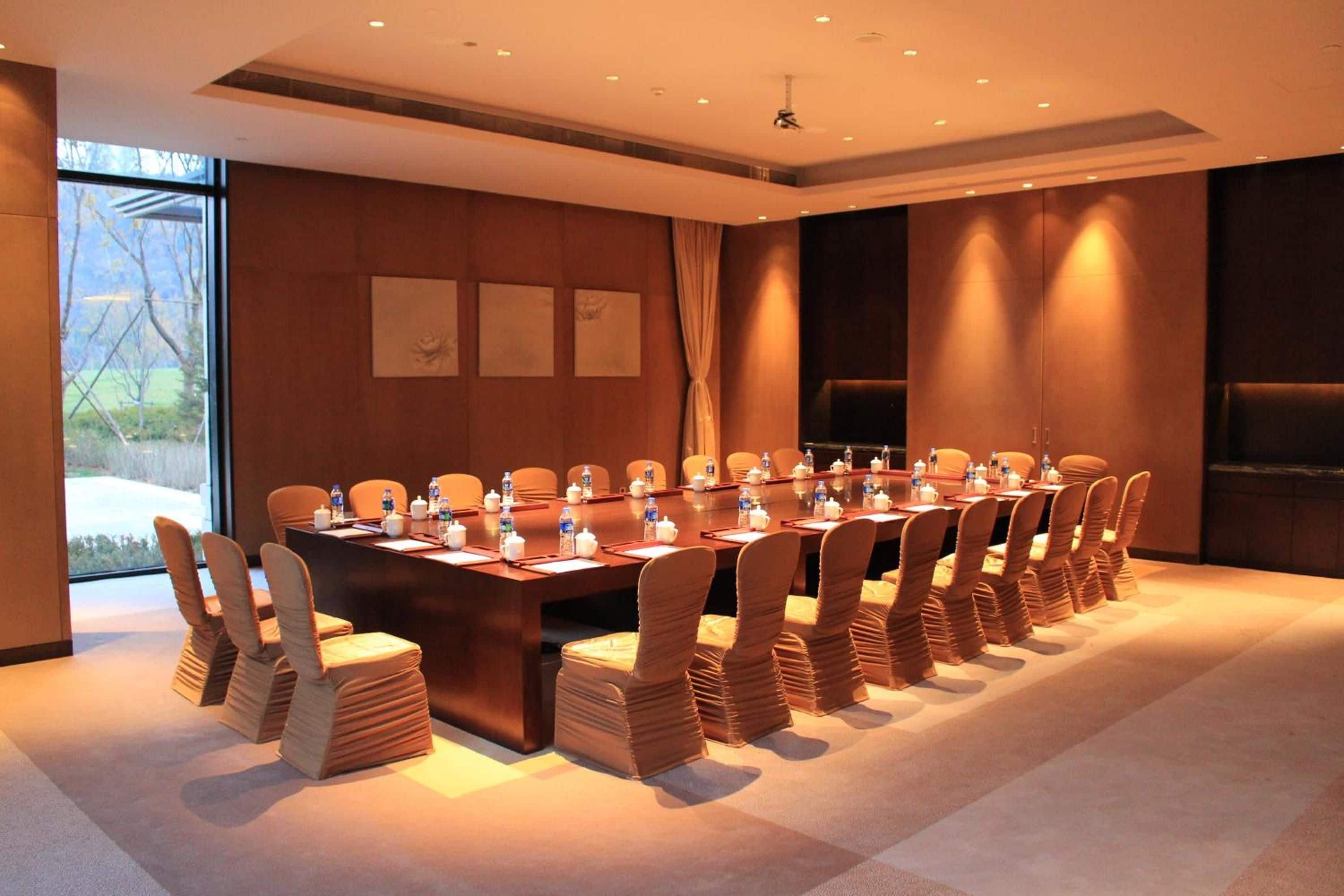 A conference room with a long table, chairs, and a projector screen.