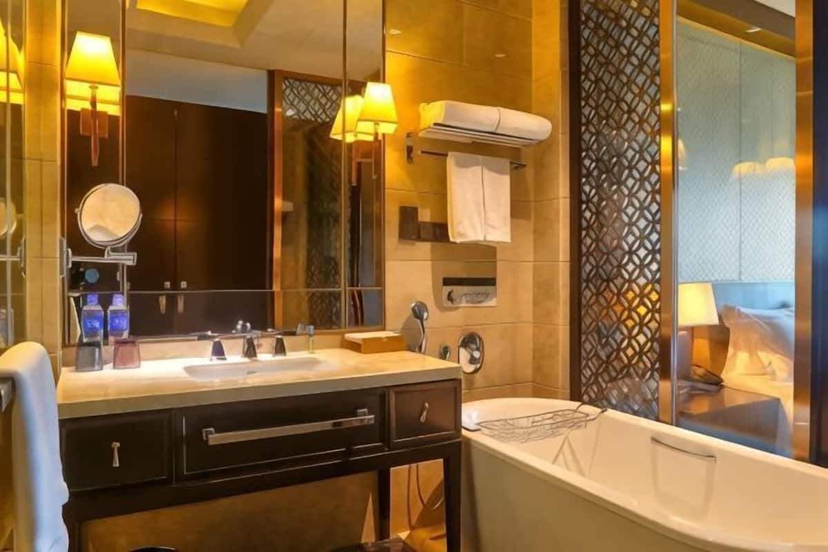 A modern bathroom with a double sink, a large mirror, a bathtub, and a decorative partition.