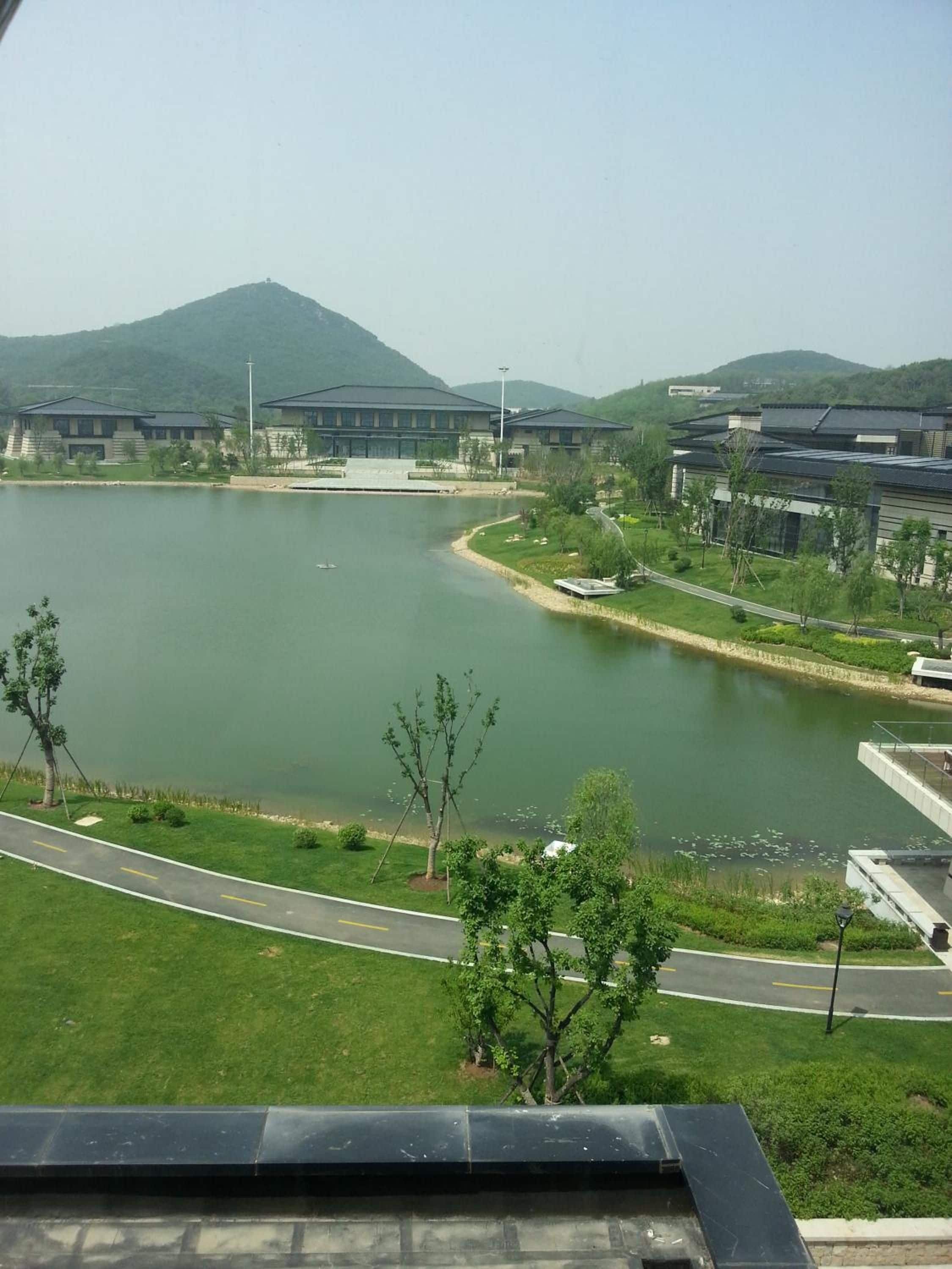 A lakeside view with buildings, a road, and a mountain in the background.