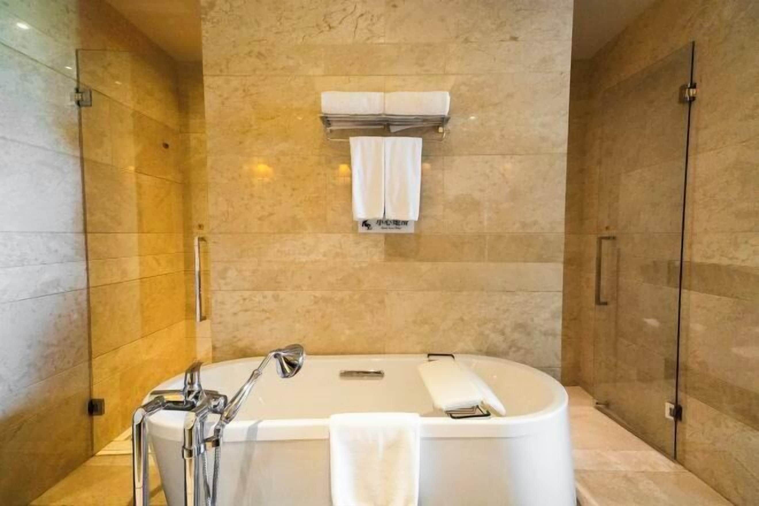 A modern bathroom with a freestanding bathtub, a glass shower enclosure, and a towel rack with two towels.