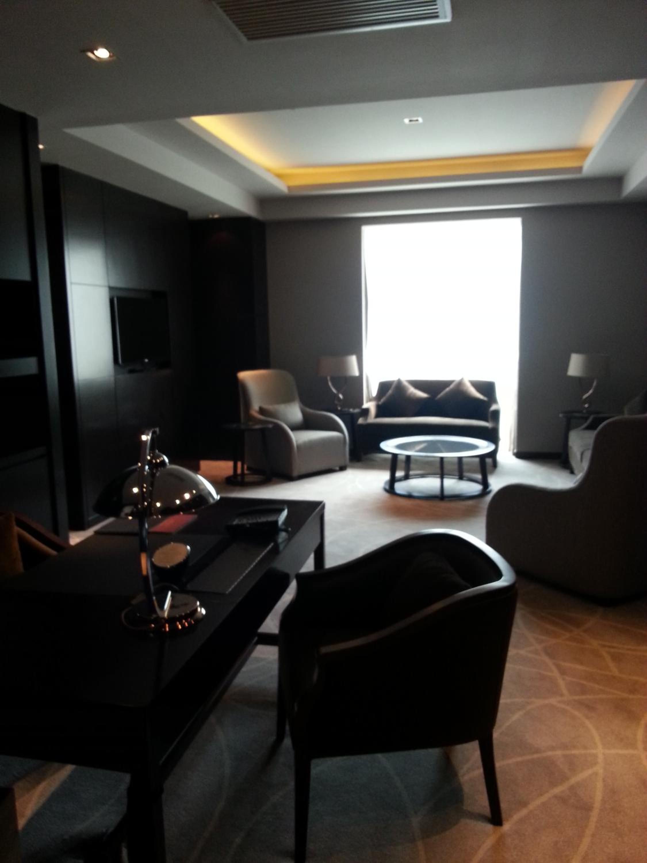A modern living room with a sofa, armchairs, a coffee table, and a TV.
