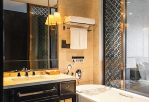 A modern bathroom with a large mirror, a sink with a towel rack, a toilet, and a shower area.