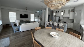 Ein großzügiger Wohnbereich mit Esstisch, Sofa und einer Küche im Hintergrund.