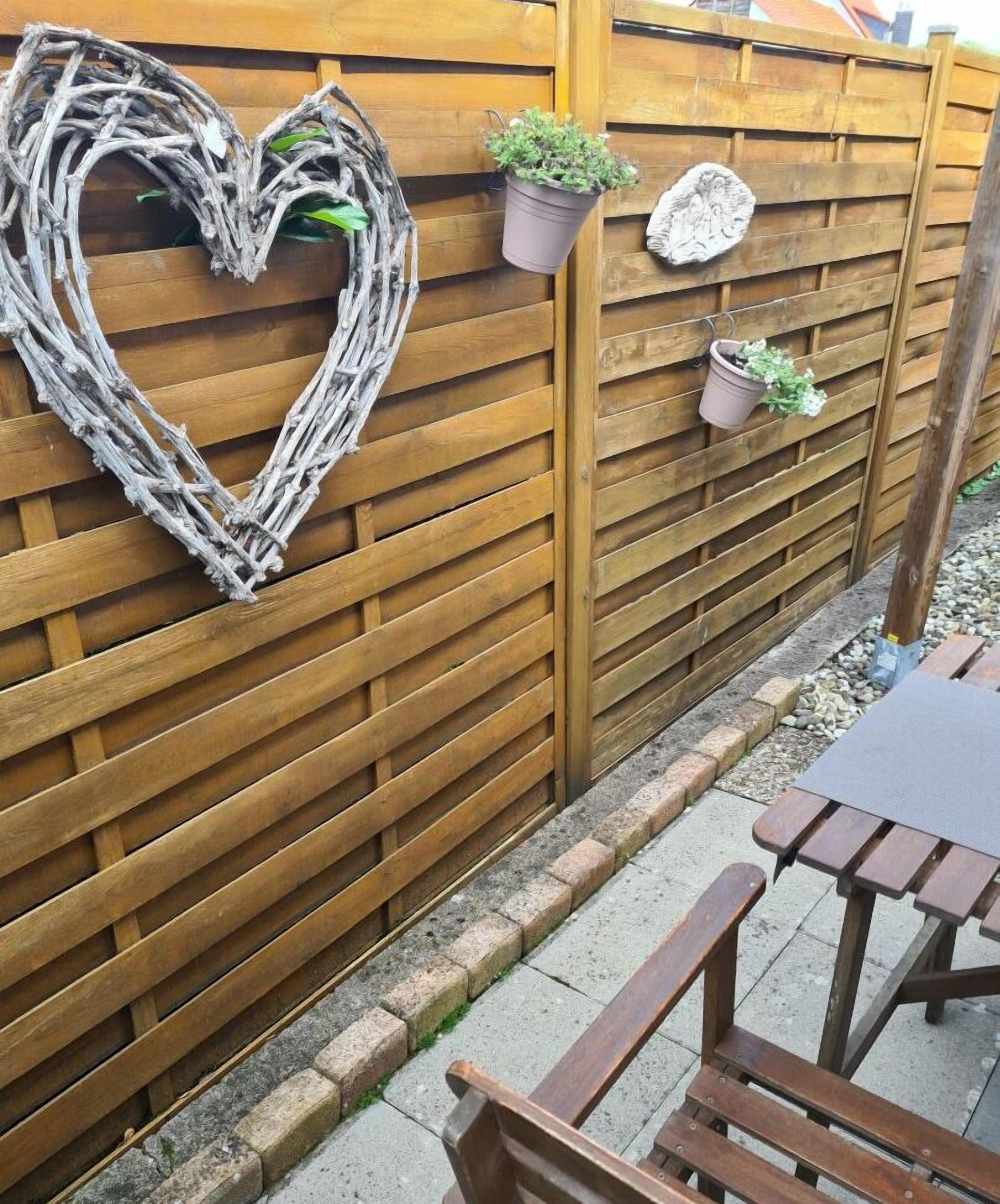 Una cerca de madera con un adorno con forma de corazón y dos macetas.