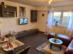 Een moderne woonkamer met een Galaxy S20 5G, een televisie, een bank en een eethoek met een tafel gedekt voor twee personen.