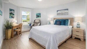Un dormitorio con una cama grande, mesitas de noche, un escritorio y sillas.