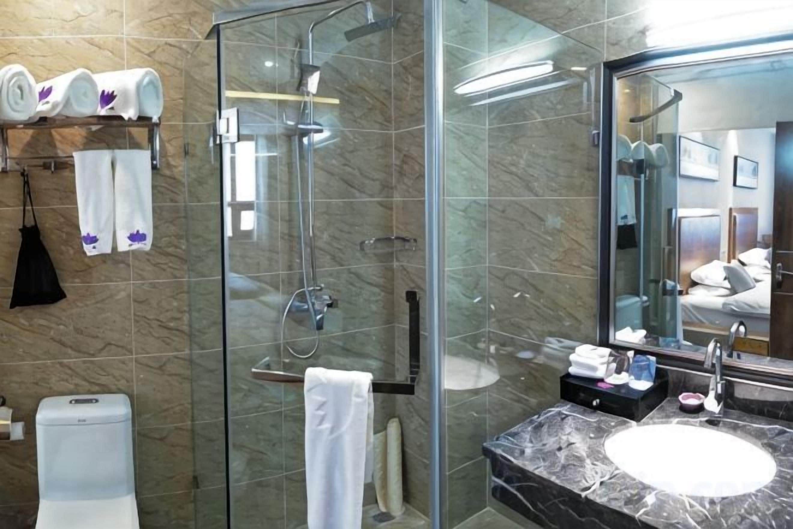 A modern bathroom with a glass-enclosed shower, a marble sink, and a large mirror.