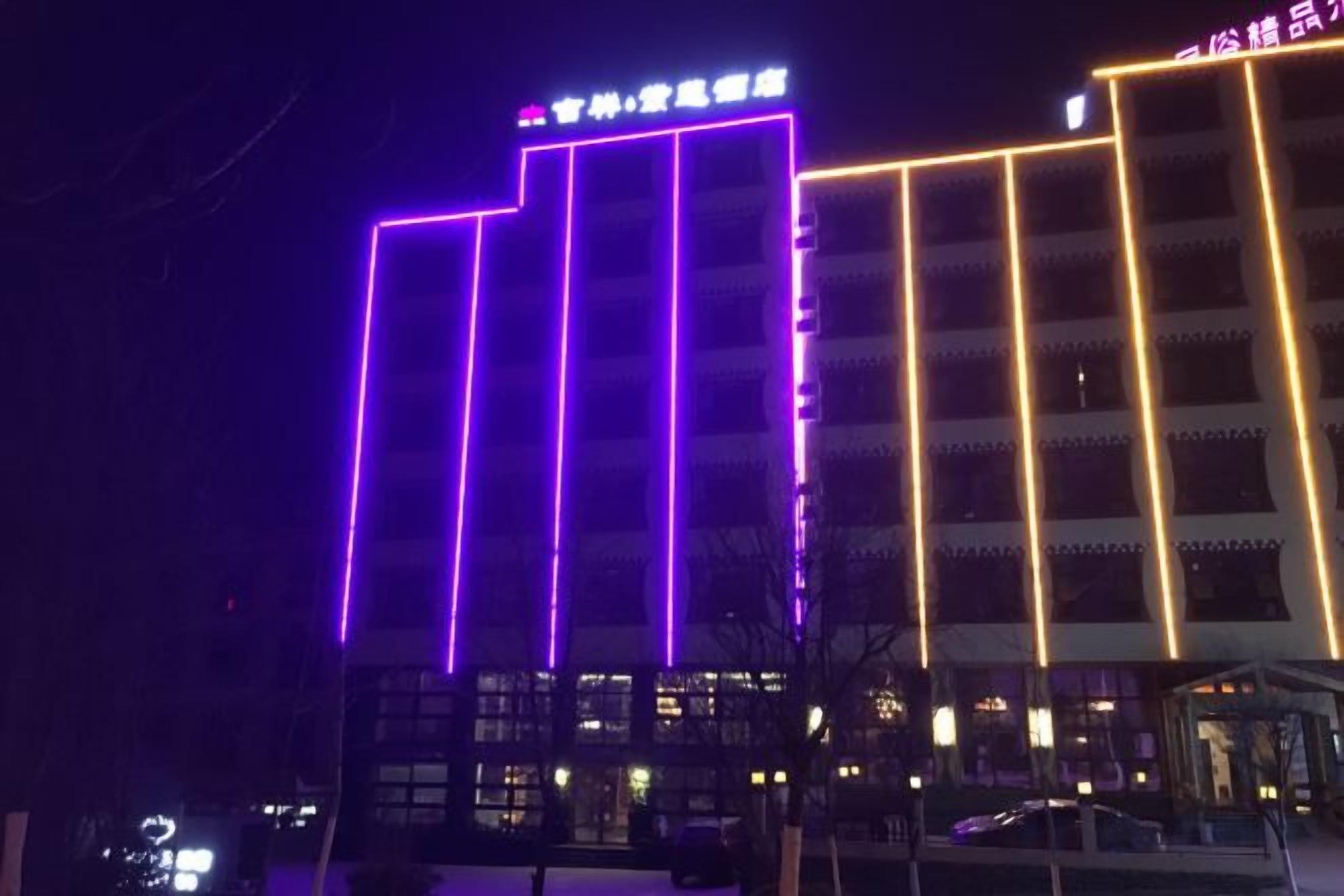 A building with illuminated vertical lines and a sign at the top.
