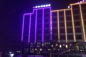 Een gebouw met verlichte verticale lijnen en een bord aan de bovenkant.