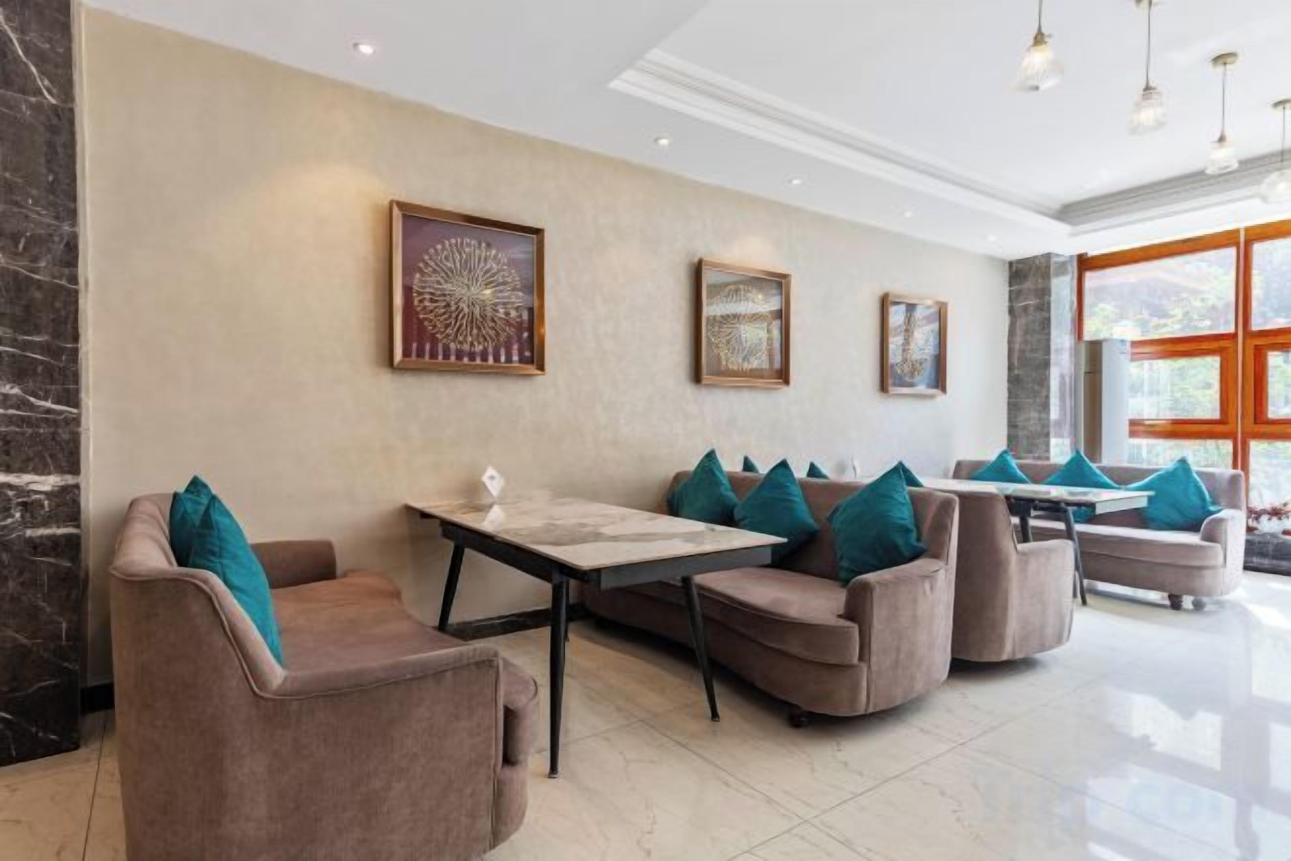 Un moderno vestíbulo de hotel con una pared de mármol, una zona de comedor con una mesa y sillas, y obras de arte en la pared.