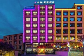 Un edificio de hotel de varios pisos con ventanas iluminadas y una entrada destacada.