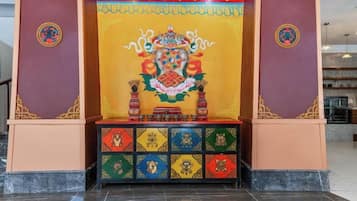 A room with a traditional altar, a prayer wheel, and a colorful tapestry.