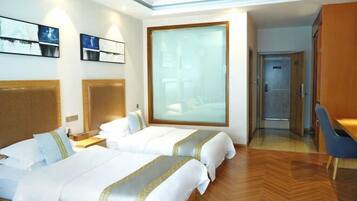 Una habitación de hotel con dos camas, un ventanal grande, un escritorio y un armario.