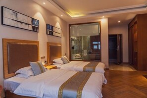 Habitación de hotel con dos camas, un espejo grande y piso de madera.