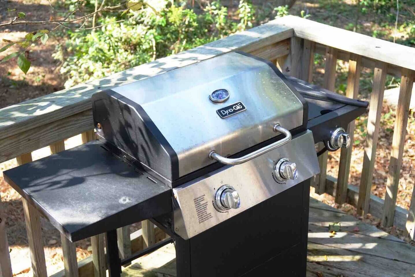 A portable gas grill with a digital display, placed on a wooden deck.