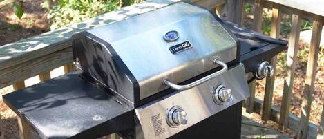 A portable gas grill with a digital display, placed on a wooden deck.