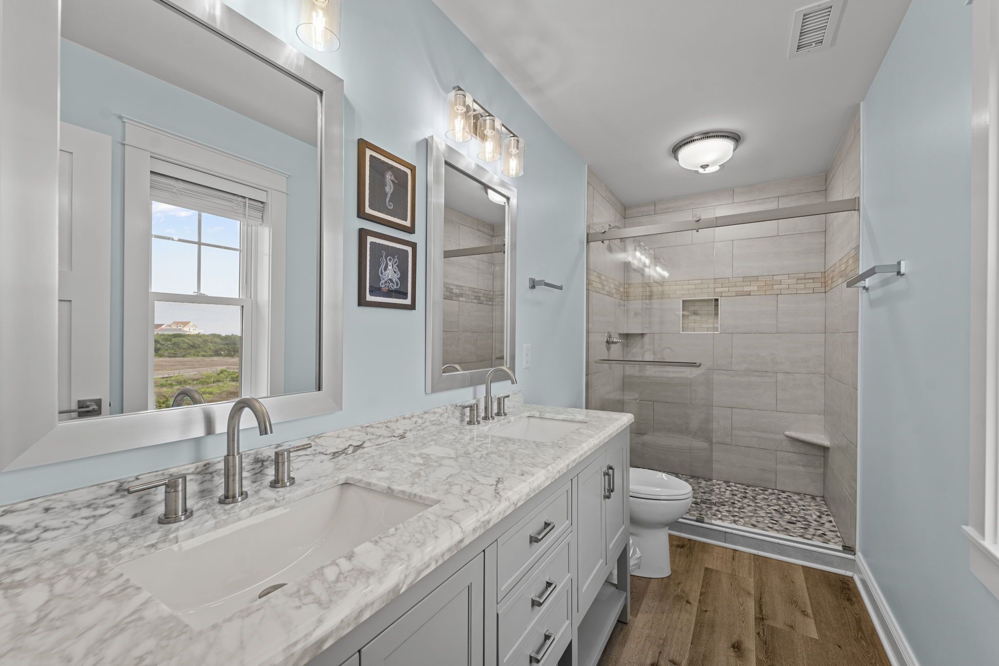 A modern bathroom with a double sink vanity, a large mirror, and a walk-in shower.