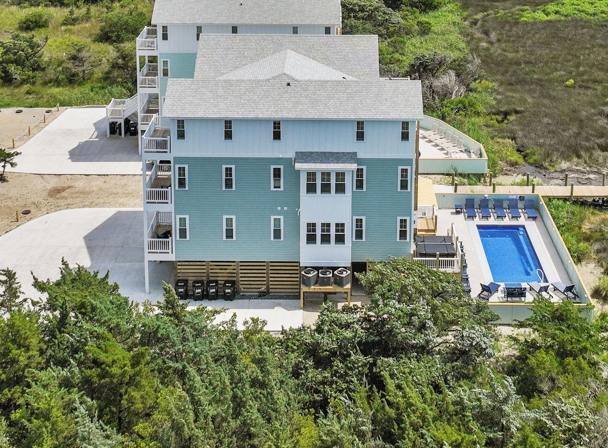 A multi-story hotel with a pool, outdoor seating, and a wooden deck.